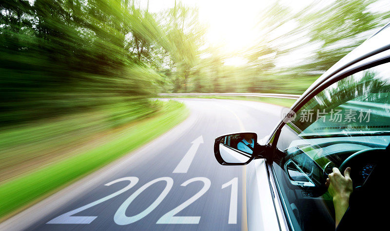 Man hand driving a car through a forest, with number 2021 on the ground